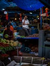 A vegetable vendor talking on a mobile phone covering his face with a mask to protect from Covid-19